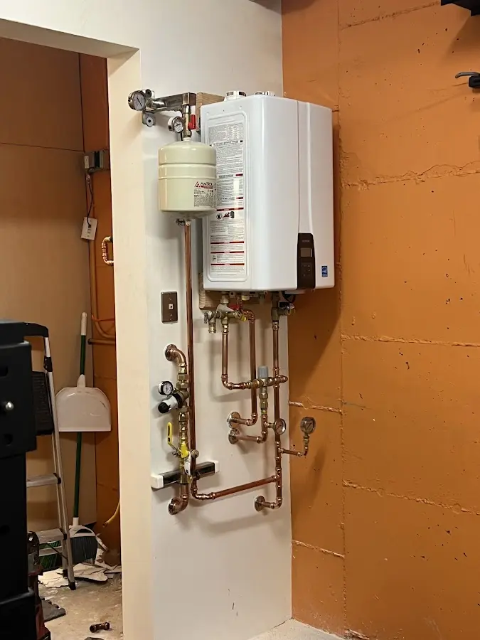 Plumbing technician inspecting water heater connections in Grand Haven